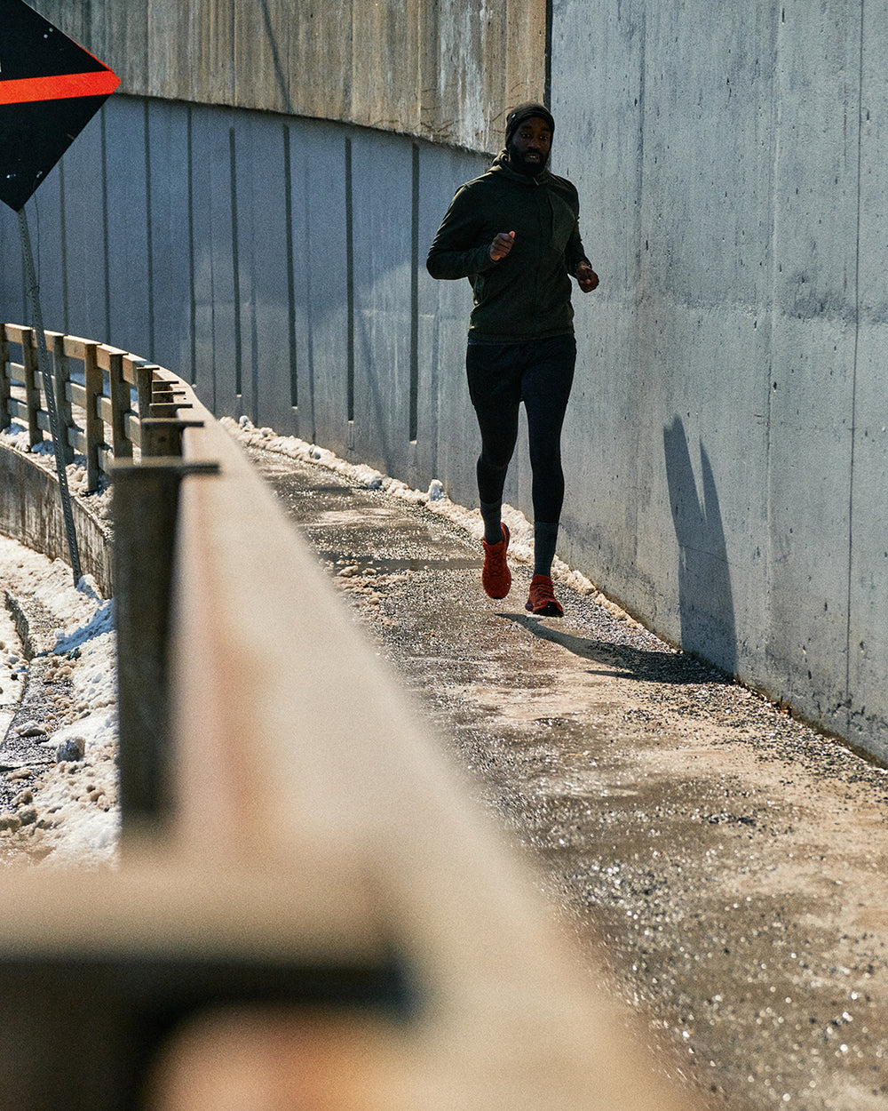 Person running on a path next to a concrete wall, wearing sports attire.