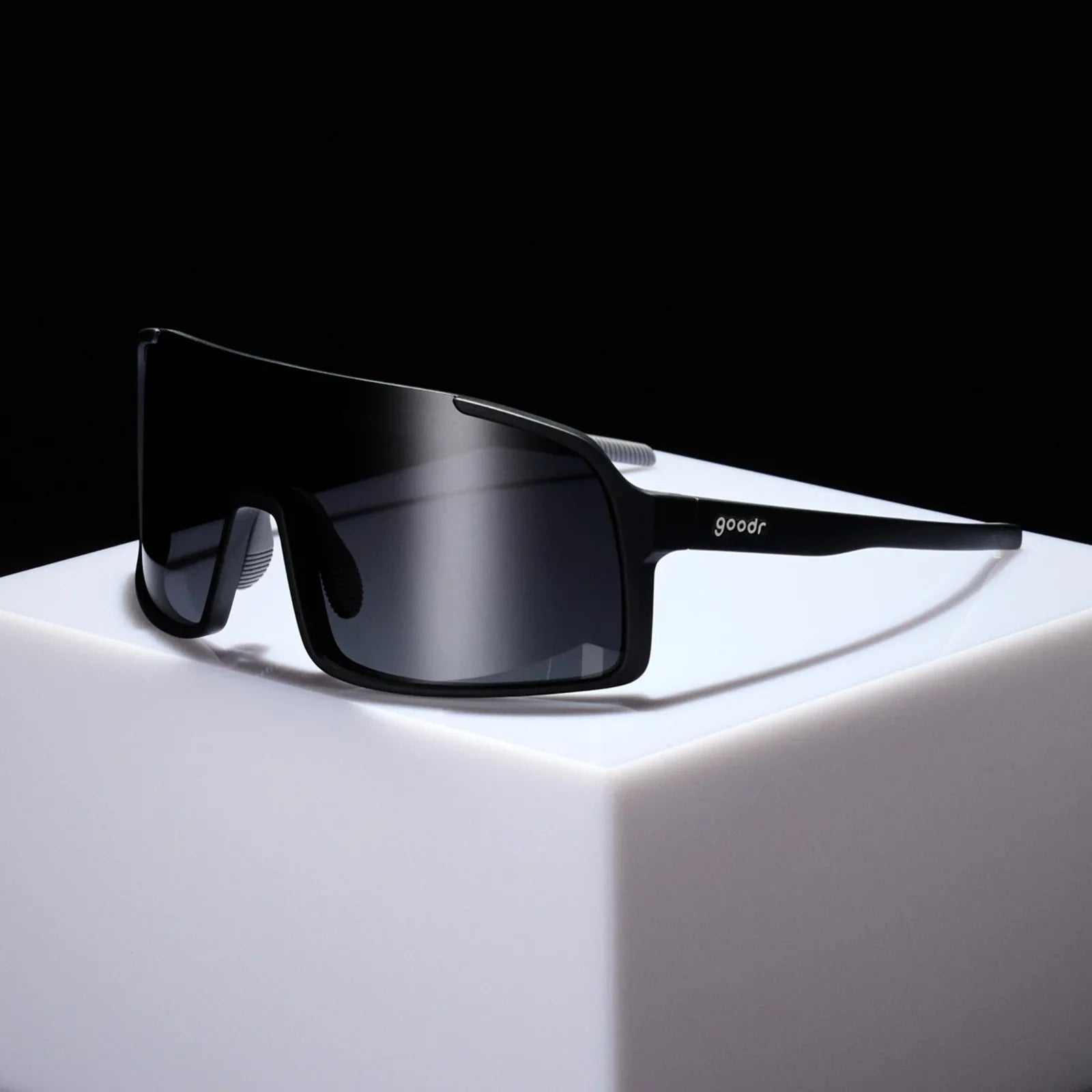 Black shield sunglasses with black gradient lenses on white pedestal.