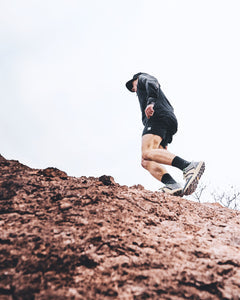 Person running uphill in a relaxed fit hoodie made of recycled polyester and organic cotton.