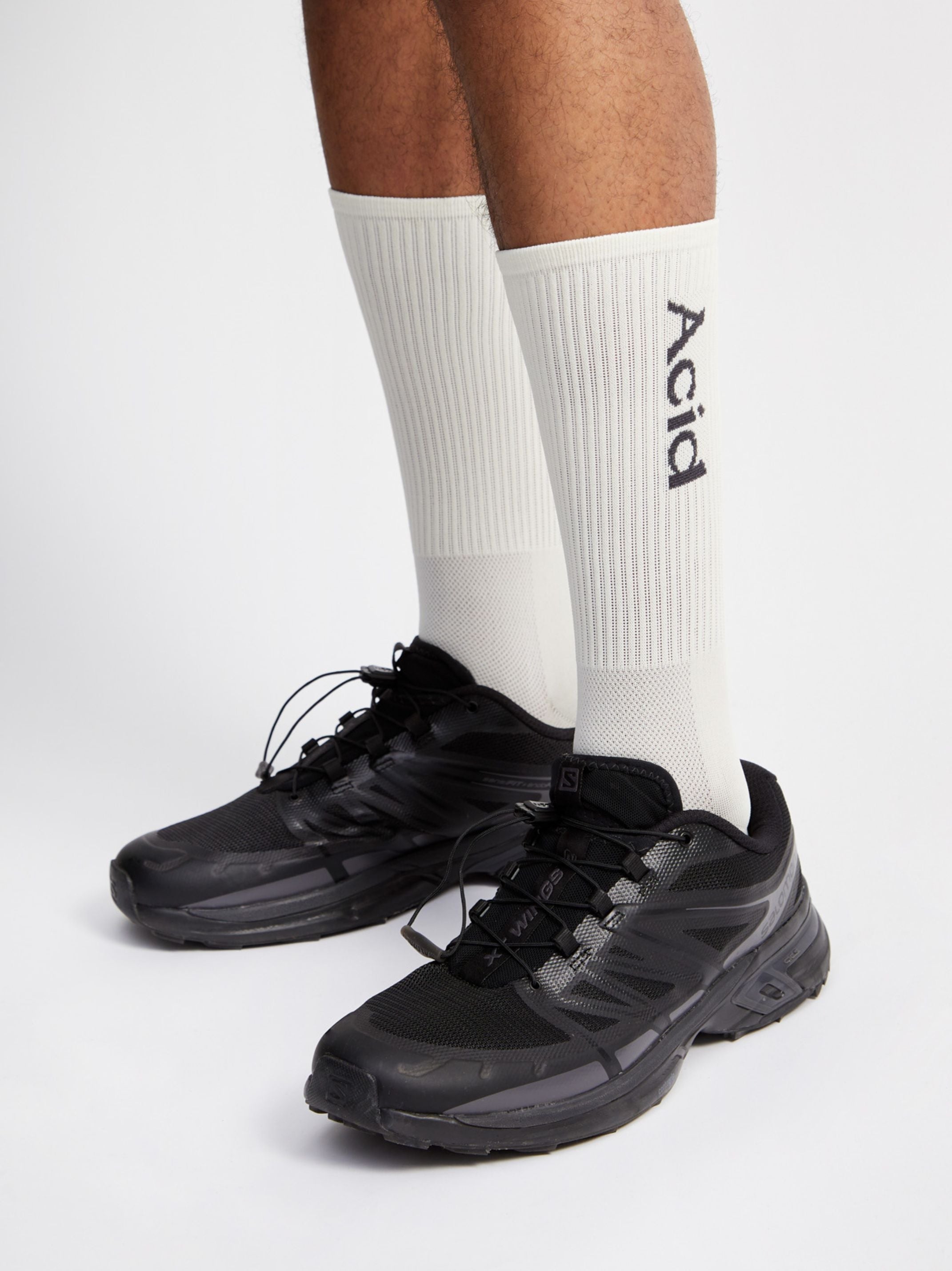 Bone and black logo socks above ankle, lightweight and breathable for runners.