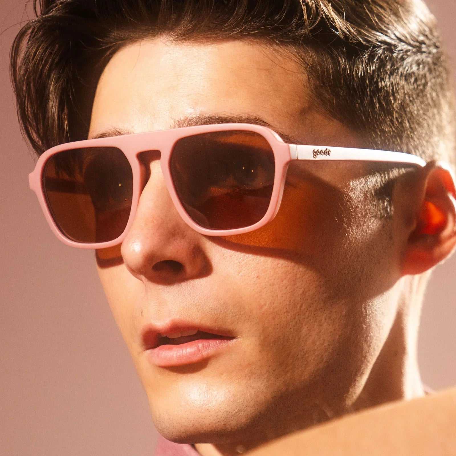 Pink sunglasses titled "Threaten Me With a Good Time" worn by a person.