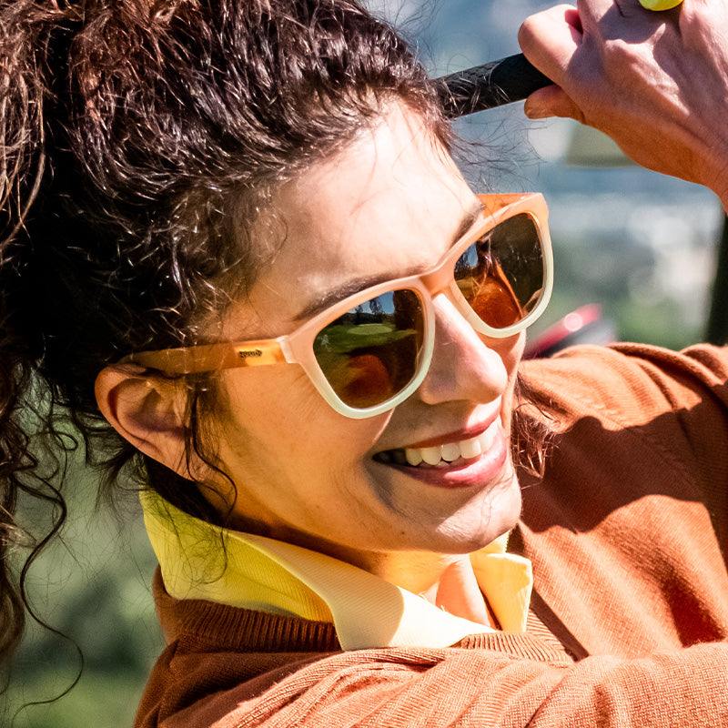 Woman wearing Three Parts Tee sunglasses with brown gradient polarised lenses on a golf course.