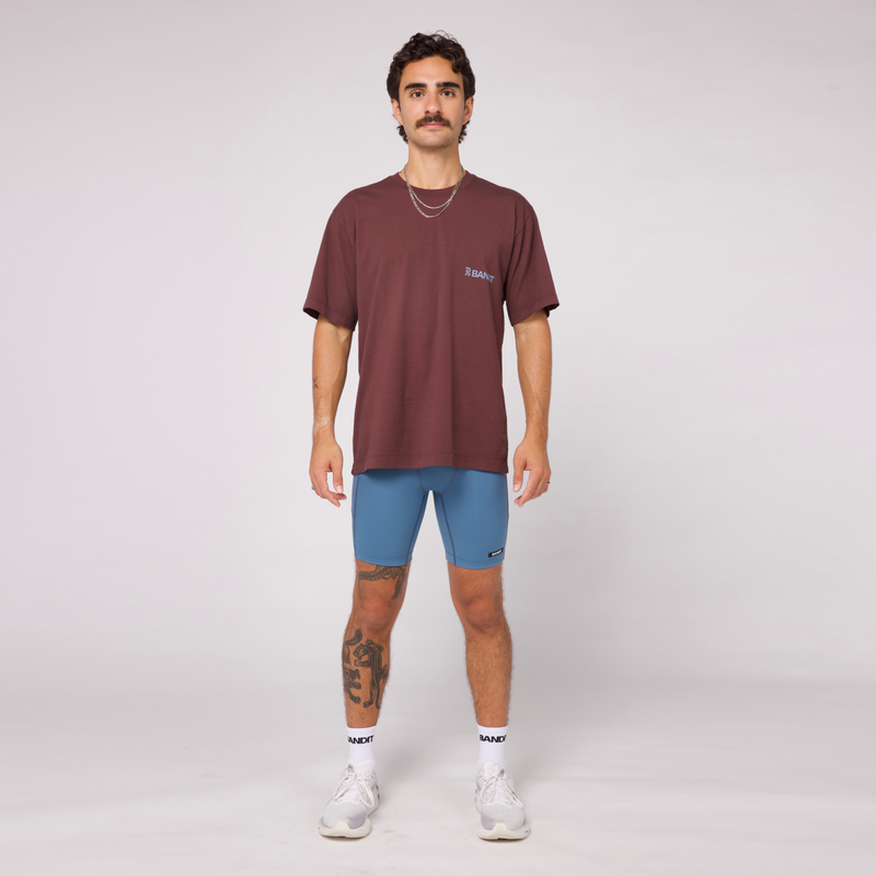 Community Tee Unisex in Chocolate with Smokey Blue print, featuring a relaxed fit and crew neckline, made from 100% combed cotton.