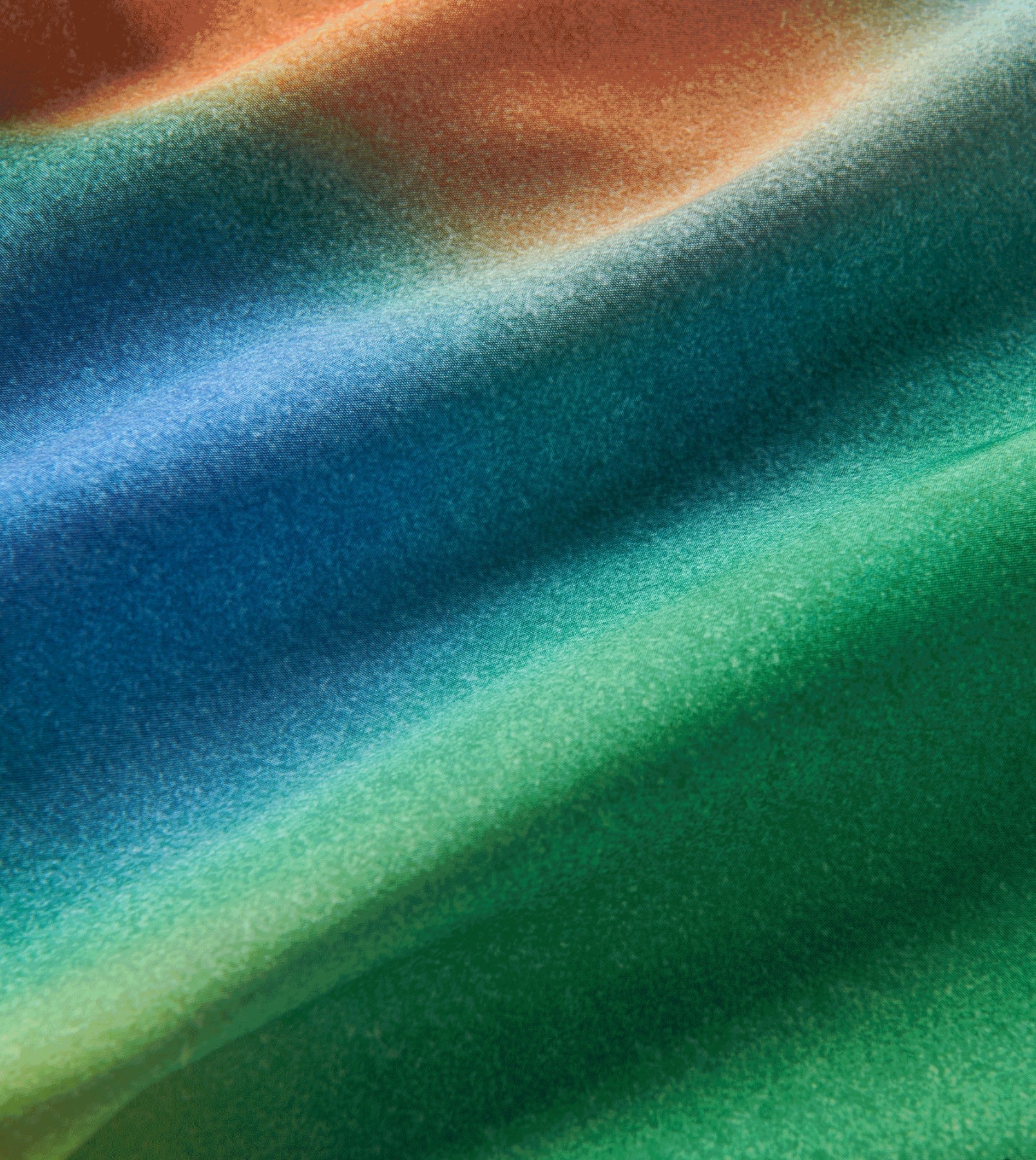 Close-up of vibrant, tie-dye fabric used in Alta Shorts 5", featuring blue, green, and orange hues.