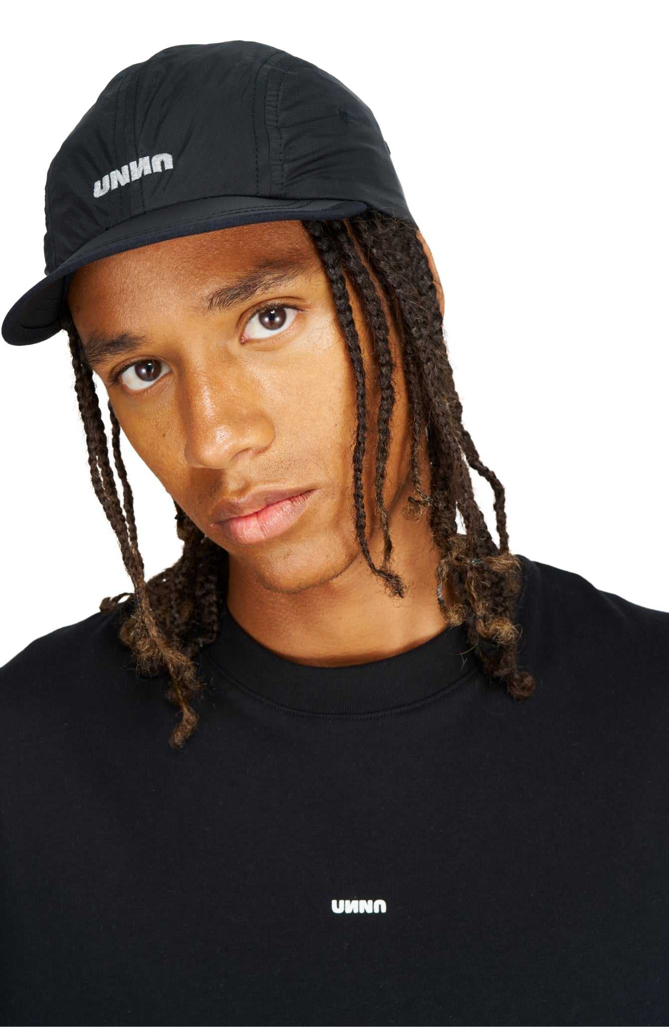 UNNA Smiles Run Cap in black GRS recycled polyester, water repellent, PFC free, with logo and adjustable strap.