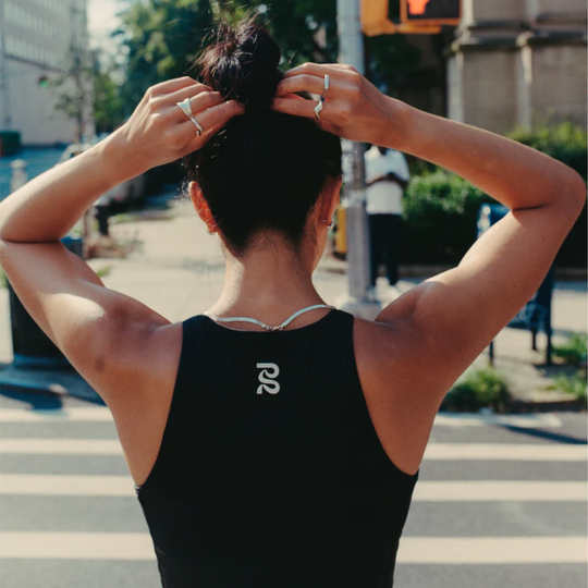 Back view of a person wearing the Stamina Luna Race Crop in black, displaying the reflective graphic and halter silhouette.