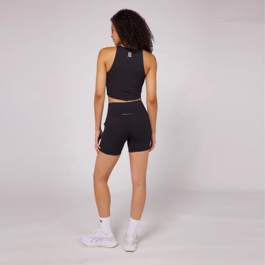 Stamina Luna Race Crop, back view, model wearing black sleeveless crop top with shorts, showcasing reflective graphic and sports design.