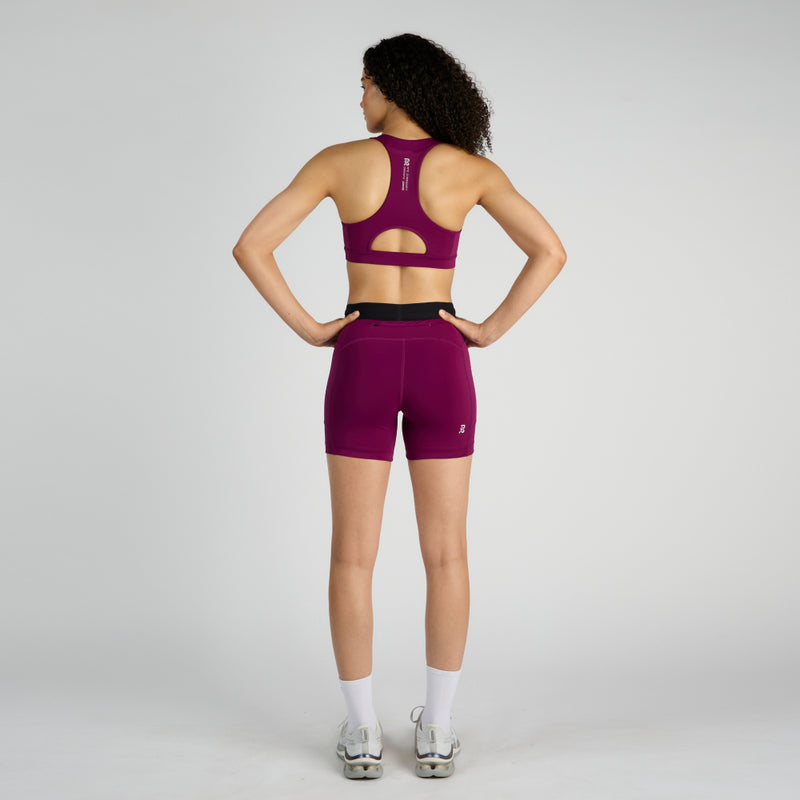 Stamina™ 5" Women's Compression Shorts in vibrant plum color, featuring dual anti-bounce pockets and a zippered stash pocket, worn by a model from the back view.