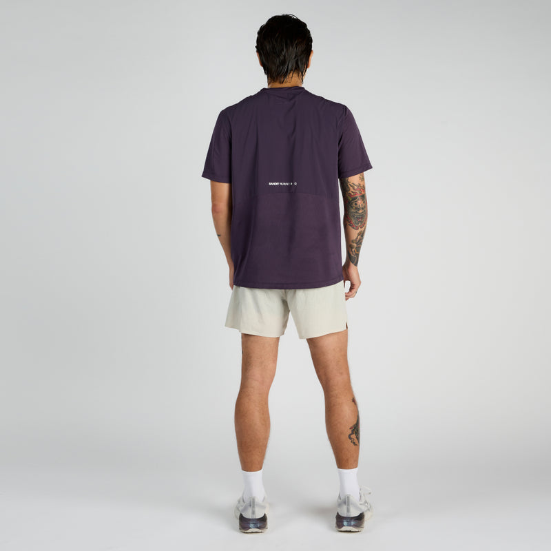 Man wearing Vento™ Performance Tee Pieced in purple standing with back view, showing reflective graphic details.